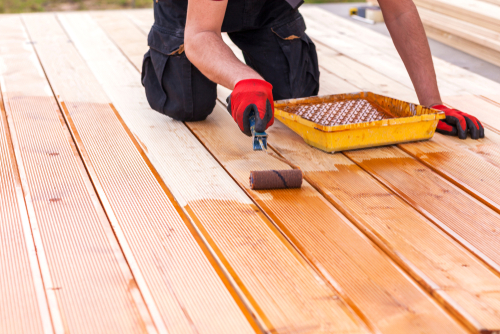 man sealing terrace board for outdoor deck attachment
